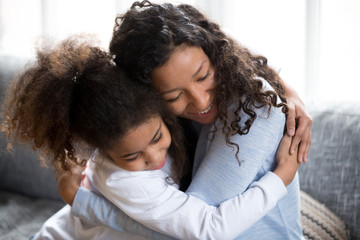 Happy African American mom and daughter hug making peace