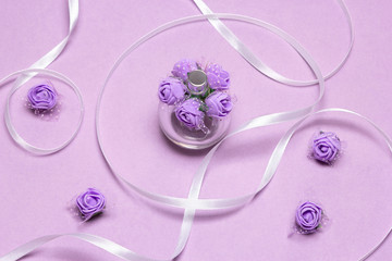 Perfume spray bottle with small lilac roses and white satin ribbon. Fragrance as gift for woman
