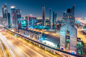 Obraz na płótnie Canvas Colourful nightime skyline of Dubai, United Arab Emirates. Aerial view on highways and skyscrapers.