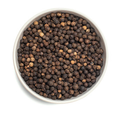 Black dried pepper in bowl isolated on white background. Top view