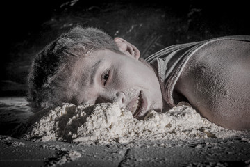 dead сhinese guy lying on the floor with a dirty face in white powder on a black background. сoncept of absolute indifference, tragedy and human hopelessness.  toned in sepia color, instagram.