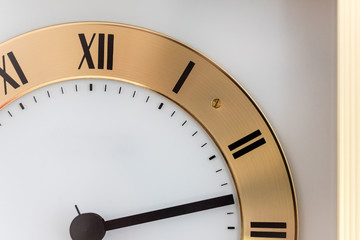 golden and white clock in front of a white wall