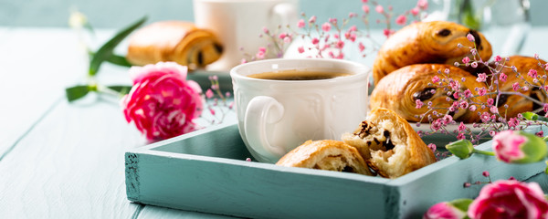 Holiday break with cup of coffee, mini fresh croissants chocolate bun and carnation flowers on...