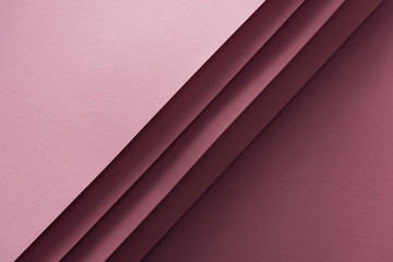 top view of blank and pink sheets of paper on burgundy background