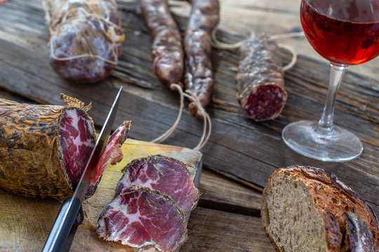 Corsican wild pork delicatessen, and cheese made in Corsica France on wooden background with glass of red corsican wine