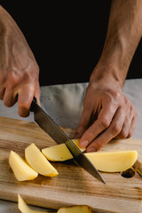 Chef's hand cutting fresh and delicious potatoes for cooking on a table. Healthy food.