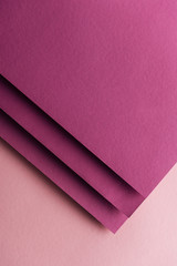 top view of blank and colorful burgundy sheets of paper on pink background with copy space