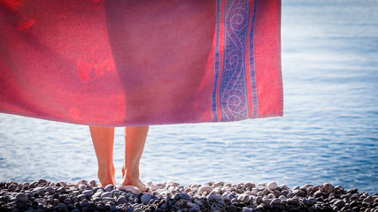Woman on beach covering hips with towel
