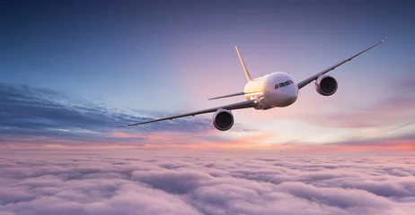 Rolgordijnen zonder boren Commercial airplane jetliner flying above dramatic clouds in beautiful sunset light. Travel concept. © Lukas Gojda