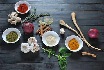 Colorful various of fresh and dried herbs, spices for cooking. Spice and herb seasoning, paprika powder, cinnamon, red onion. garlic, basil, ginger root on dark background