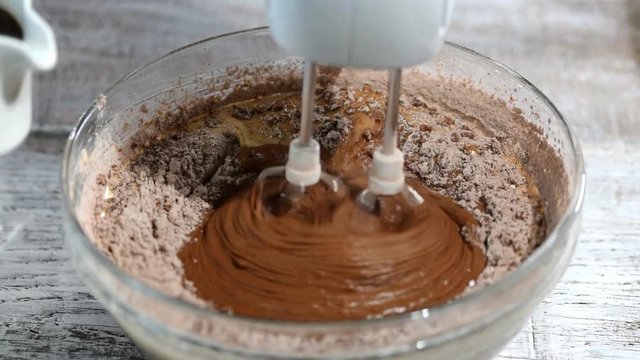 Beating chocolate batter with a mixer. Add coffee into batter