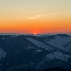 sunrise in the Carpathians on the background of blue mountain ranges and solar disk on the horizon. 