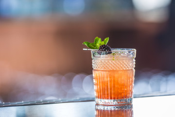 Cocktail drink bramble with black berries and mint at barcounter in night club or restaurant