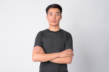 Portrait of young handsome Asian man with arms crossed