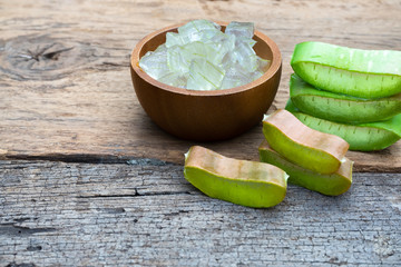 Fresh aloe vera stem slices and gel on wooden table, skin therapy concept