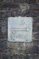 Old car park sign on stone wall