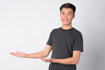 Portrait of young happy Asian man showing something