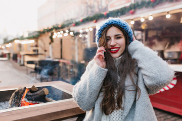 Outdoor portrait of excited brunette girl in woolen coat enjoying winter weekend in warm day. Photo...