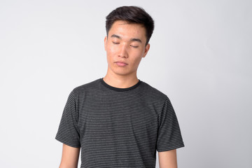 Face of young handsome Asian man relaxing with eyes closed