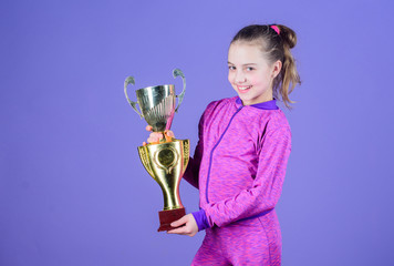 Adorable cup winner. Small girl holding silver cup. Little child with cup shaped sports trophy....