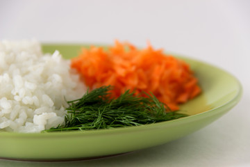 Boiled rice, carrots and dill on a white background.