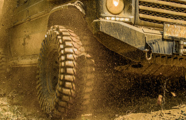 Off-road vehicle goes on mountain way. Bottom view to big offroad car wheel on country road and mountains backdrop. Tires in preparation for race. Road adventure. Adventure travel. © Volodymyr