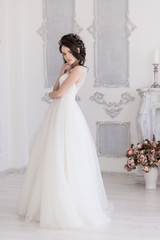 Fototapeta premium Morning of the bride. A beautiful bride stands in a wedding dress. Hand at the face.