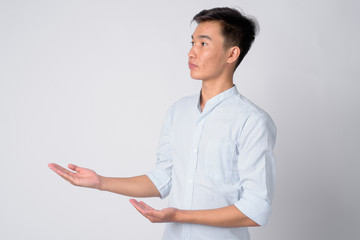 Portrait of young handsome Asian businessman showing something