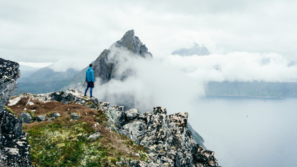  Adventurous man is standing on top of the mountain and enjoying the beautiful view during...