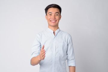 Portrait of young happy Asian businessman giving handshake