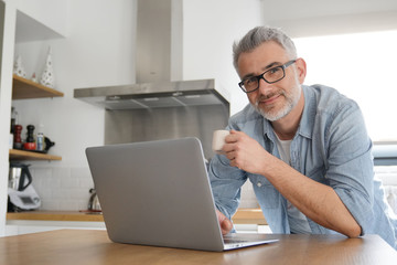 Man with computer at home in modern kitchen