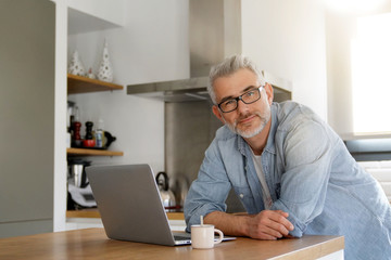 Man with computer at home in modern kitchen