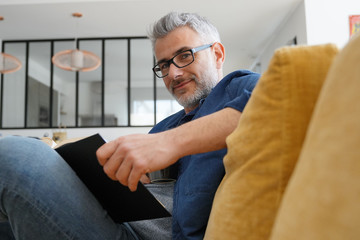 Man in 40s reading book in modern home