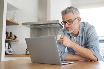 Man with computer at home in modern kitchen