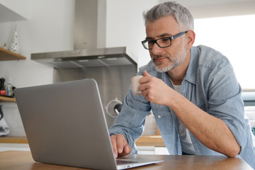 Man with computer at home in modern kitchen