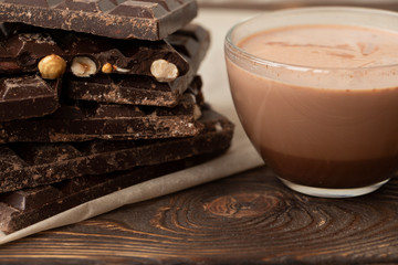 Cup of cocoa and dark chocolate on a pink wooden background