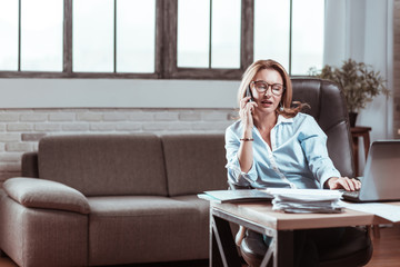 Blonde woman wearing glasses calling her business partner from work