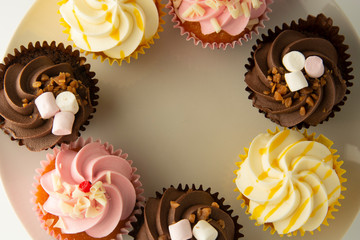 Colorful cupcakes on a white background. Pink, yellow and chocolate cupcakes. Party food. Sweet dessert or breakfast. Party, birthday food. Bright food photo. Copy space.