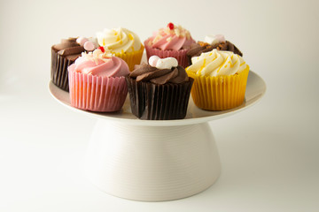 Colorful cupcakes on a white background. Pink, yellow and chocolate cupcakes. Party food. Sweet dessert or breakfast. Party, birthday food. Bright food photo.