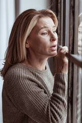 Woman feeling emotional and sad standing near the window