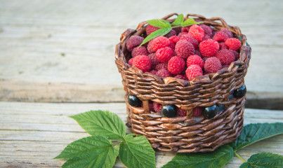ripe raspberries in a basket on a wooden background