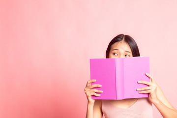 Young Asian woman with a book cover her face.