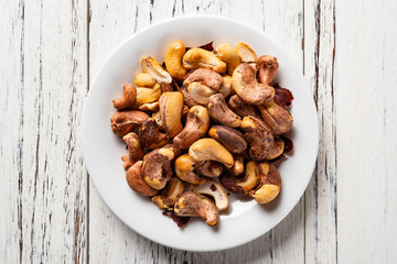 top view cashew nuts on a dish on white wood background