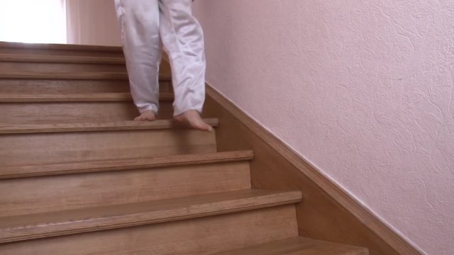 Close-up a man in white pants walking down the wooden step to first floor in modern house