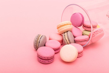 Many macaroons in a glass vase isolated on pink background