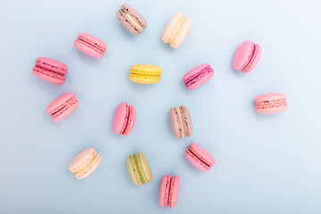 Colorful cake macaron or macaroon on turquoise pastel background from above. French almond cookies on dessert top view.