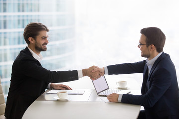Satisfied happy businessmen shake hands at business office meeting