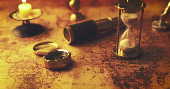 hourglass and ancient navigation items on old world map