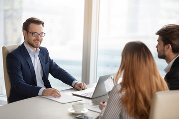 Smiling adviser manager or negotiator consulting business people at meeting