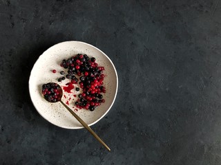 berries in white plate with spoon on dark background